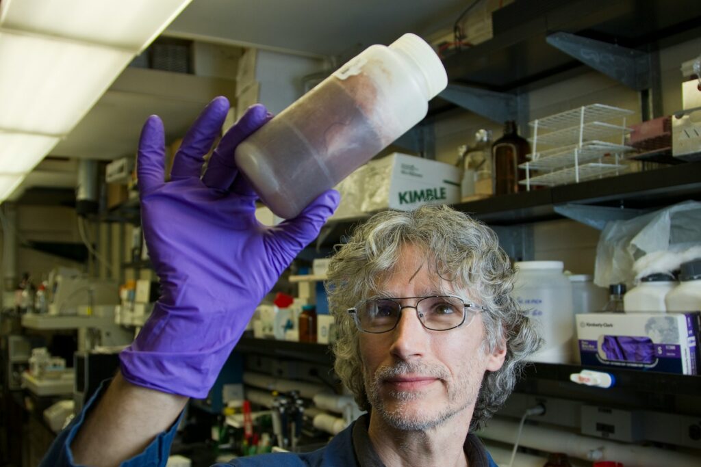 man in purple long sleeve shirt holding white plastic bottle budowie