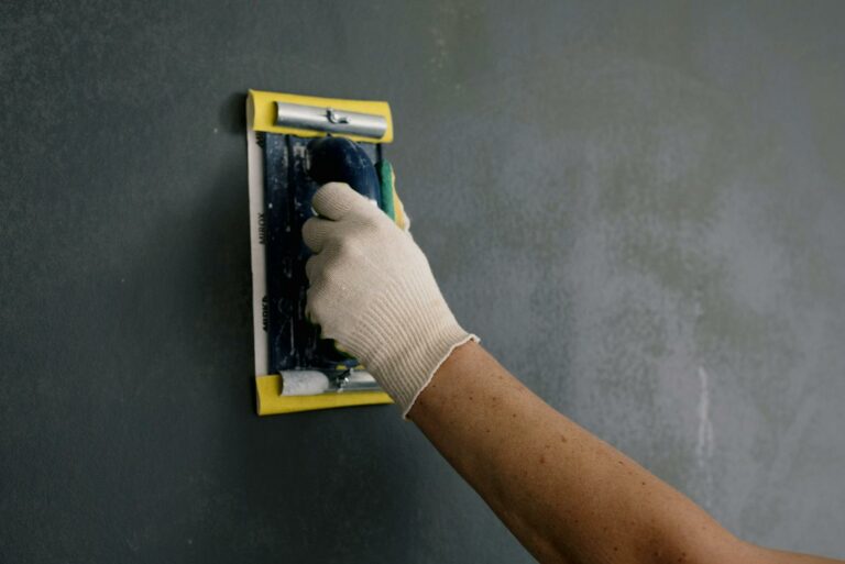 Crop man scarpering gray wall in flat